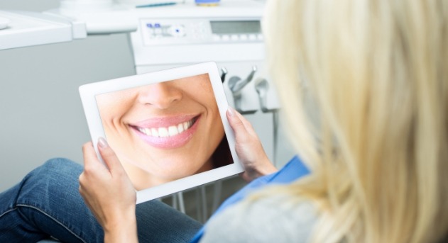 Woman looking at virtual smile design on tablet computer