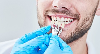 A dentist matching a patient’s enamel color for cosmetic work