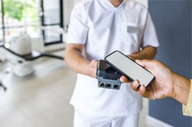 A patient using their phone to pay the cost of emergency dentistry