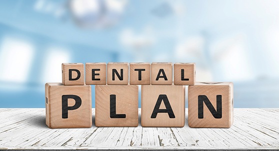 Wooden blocks spelling “dental plan” on wooden surface