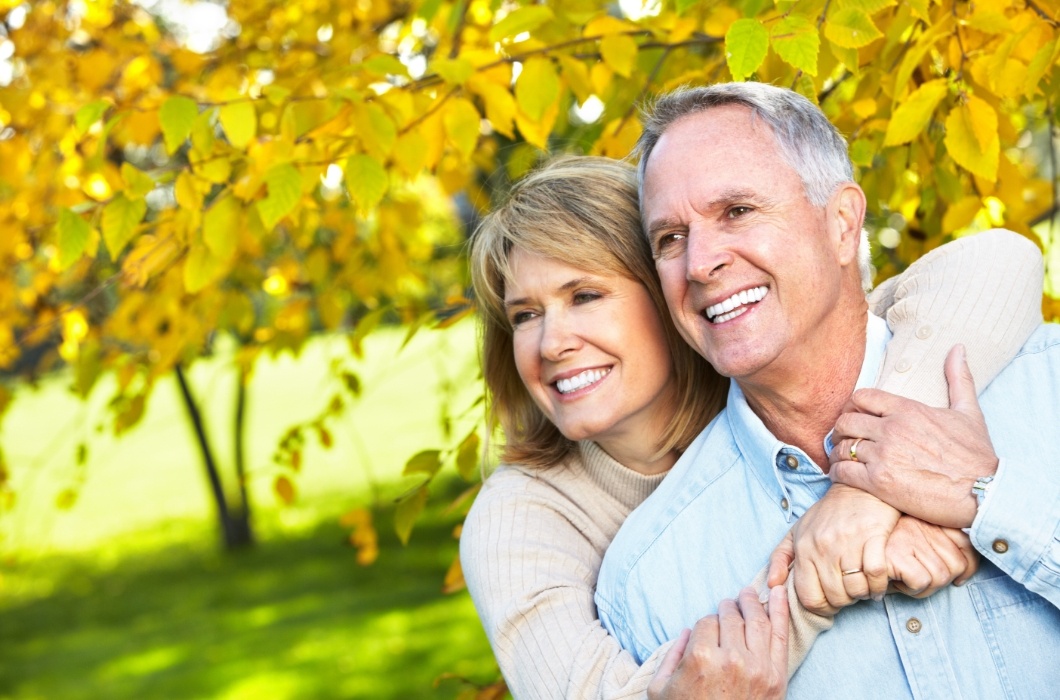 Man and woman smiling after tooth replacement with dental implants