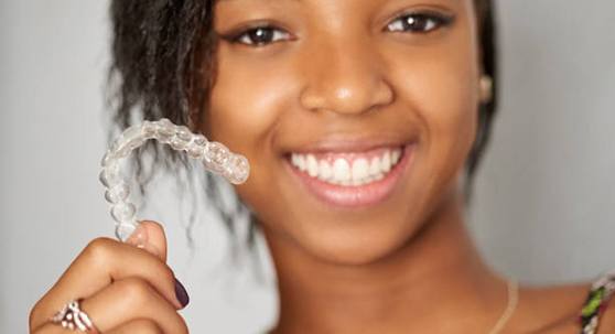 Smiling teenager holding clear aligner