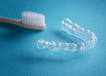 Toothbrush and Invisalign tray sitting on blue table