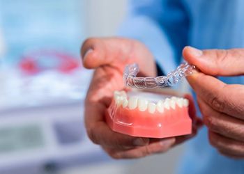 Dentist setting a tray overtop a model row of teeth