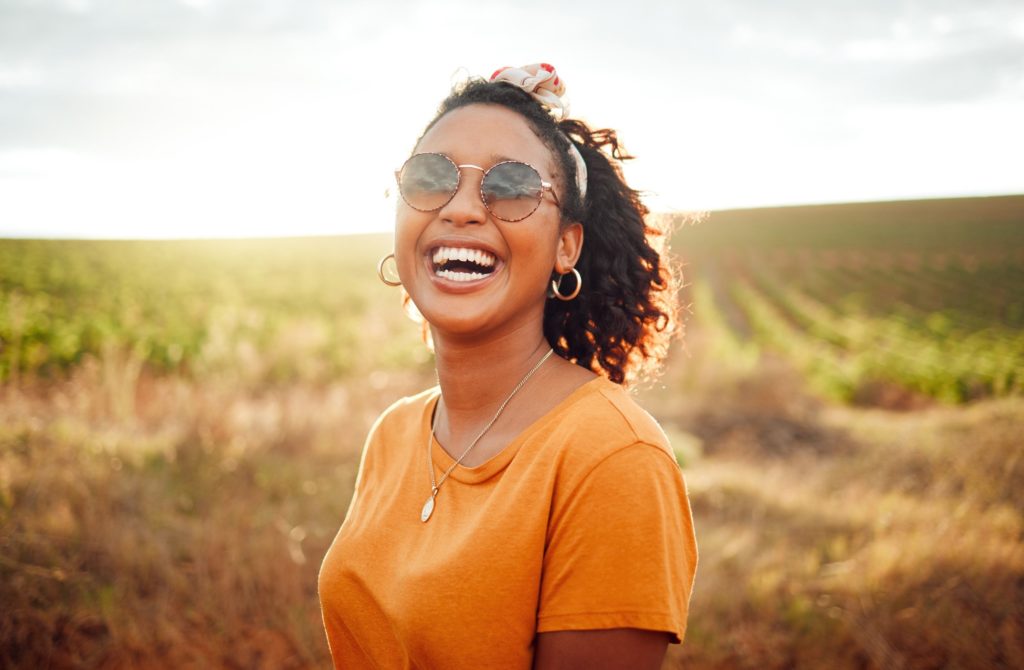 Woman in orange shirt smiling in field