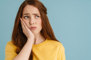 Woman holding her jaw in pain and looking concerned