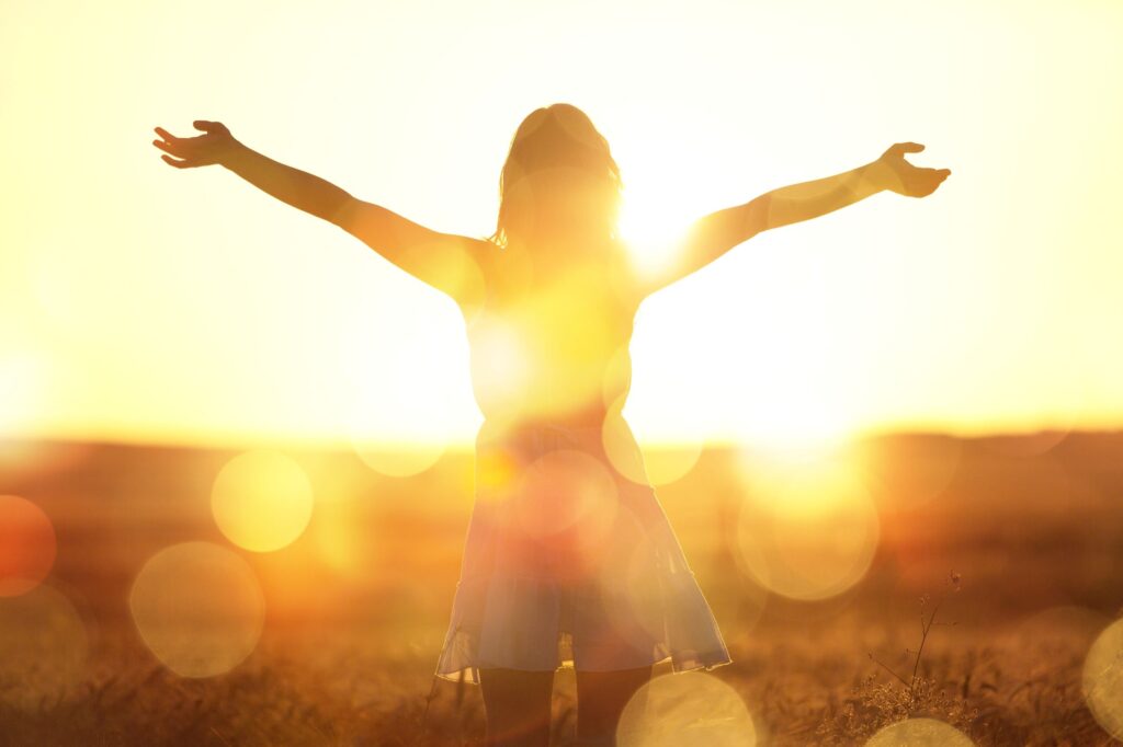 Woman in sunny field with arms outstretched